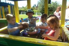 Mud mixing play in the wooden train at Ridgeway Playgroup garden